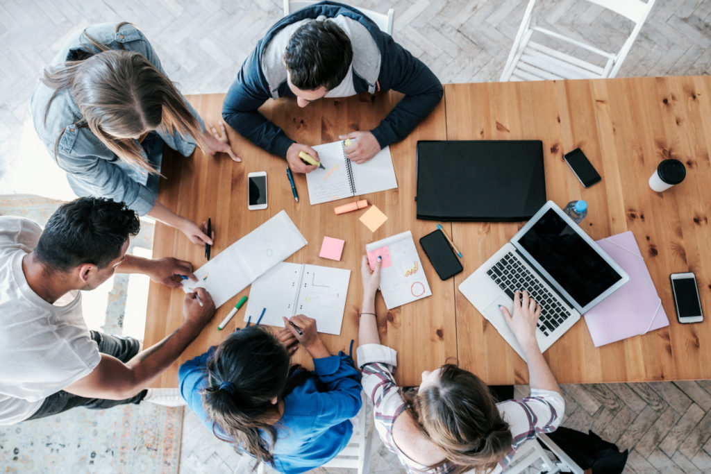 overhead view on young business people around wooden desk